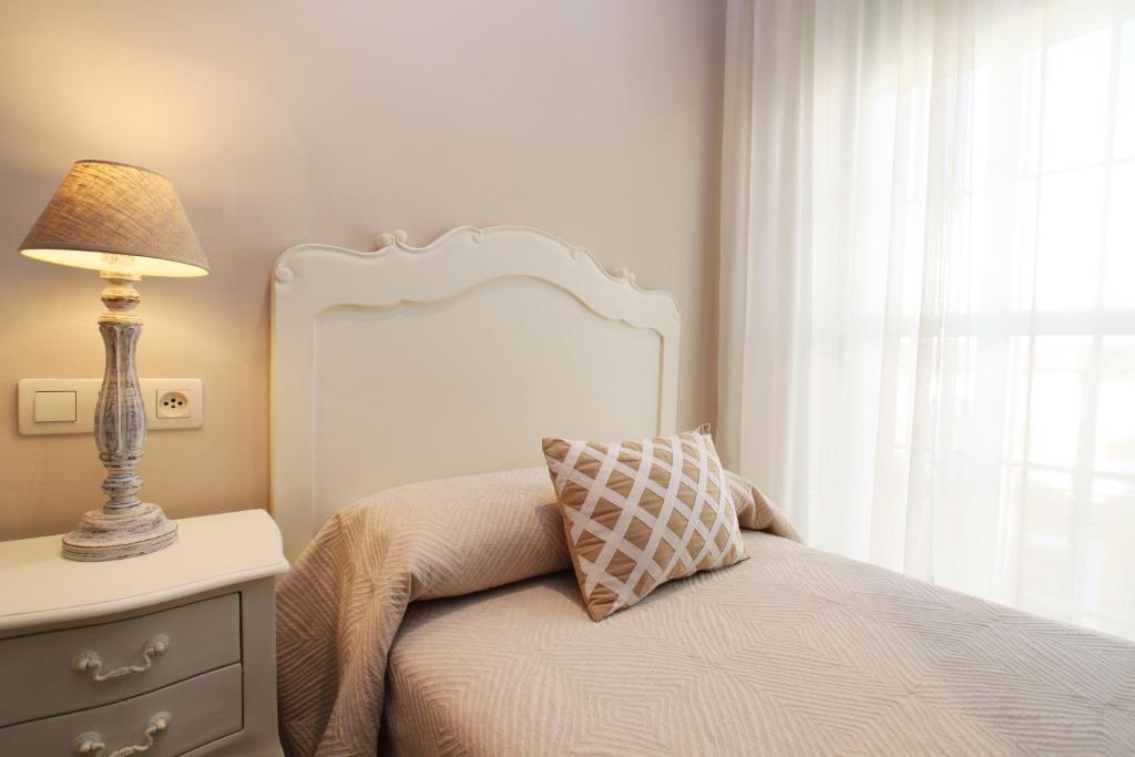 塞维利亚马斯特兰扎酒店的一间卧室配有一张带灯和窗户的床