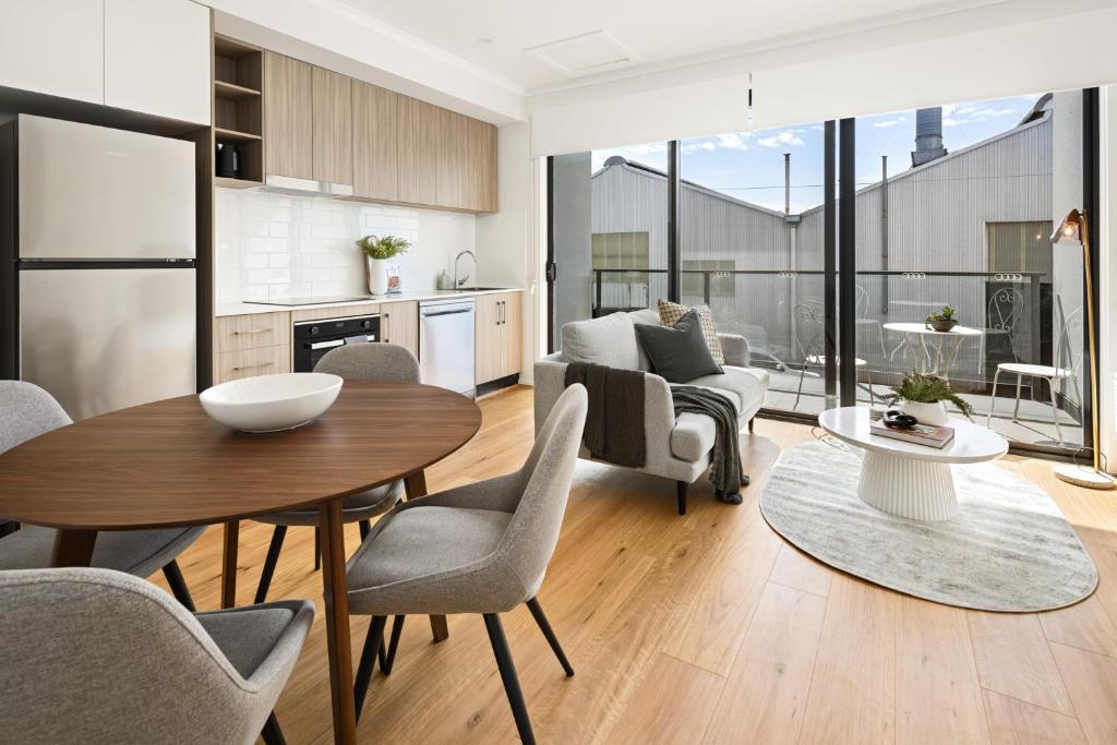 Port AdelaideClare St Apartments by Urban Rest的厨房以及带桌椅的起居室。