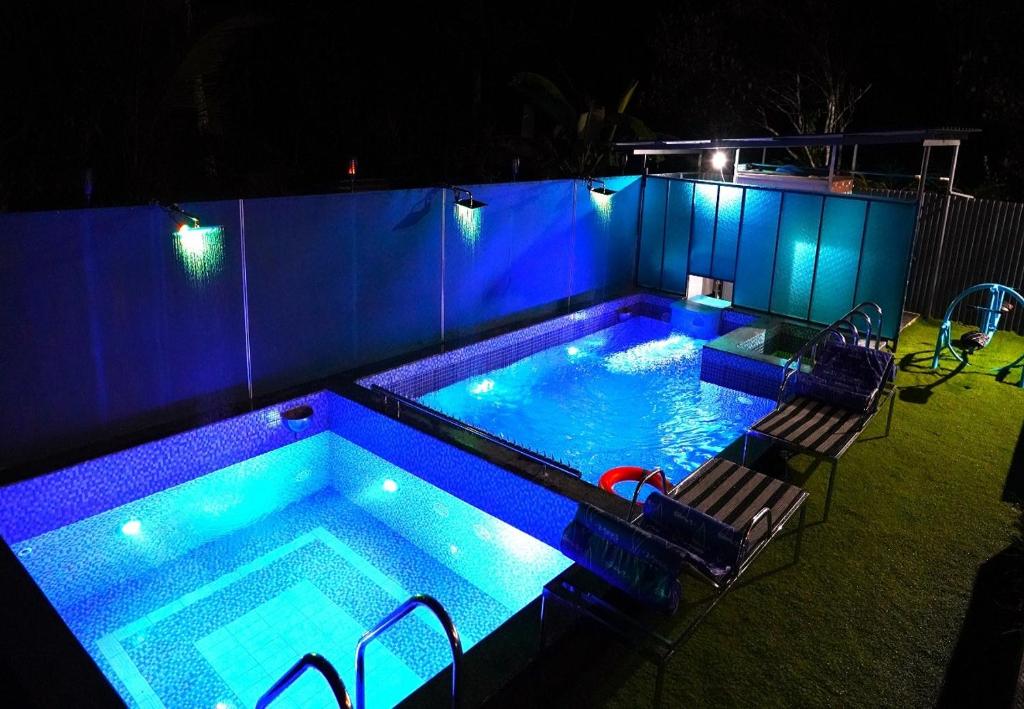蒙纳Arabian Nights Munnar的后院的游泳池,晚上有蓝色的灯光