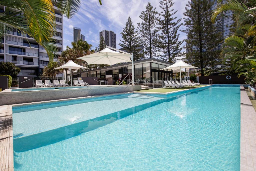 黄金海岸超景海滩酒店的一个带椅子和遮阳伞的大型游泳池