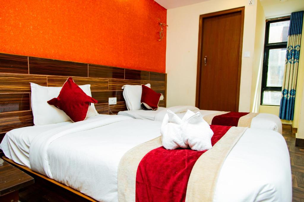加德满都Hotel Everest Regency的一间卧室配有两张带红白色枕头的床