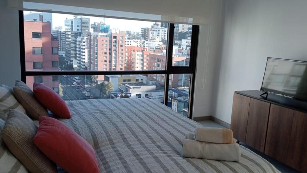 基多&ESSENCE Quito Sector Parque La Carollina Alquiler por días的一间卧室设有一张大床和大窗户