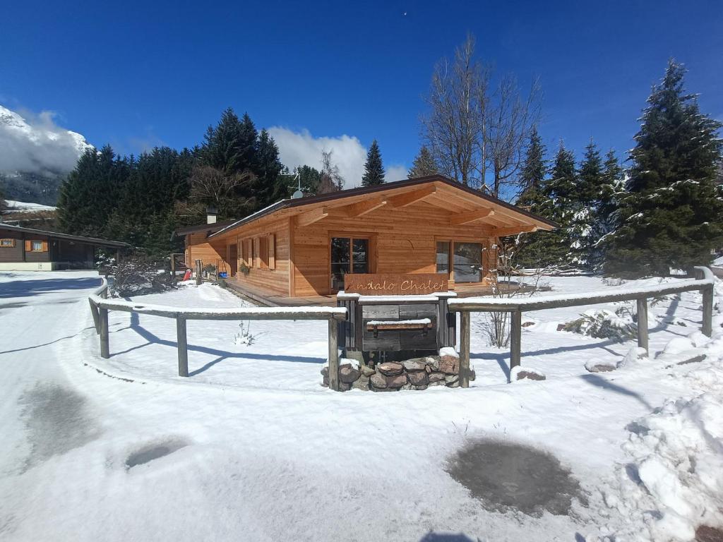 安达洛Andalo Chalet的雪地小木屋,前面有雪车