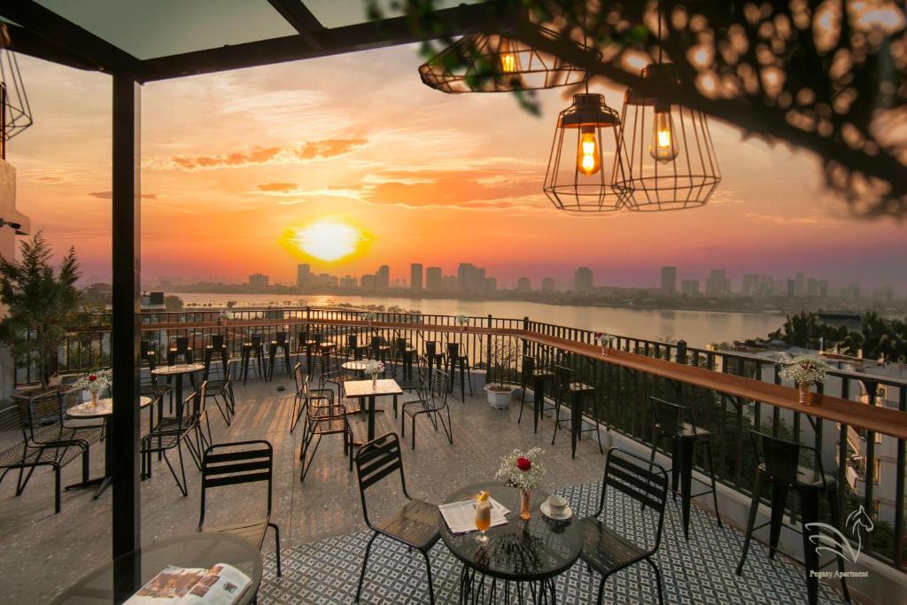 河内Westlake Pearl Apartment & Hotel - By Pegasy Group的餐厅在阳台上设有桌椅,享有日落美景