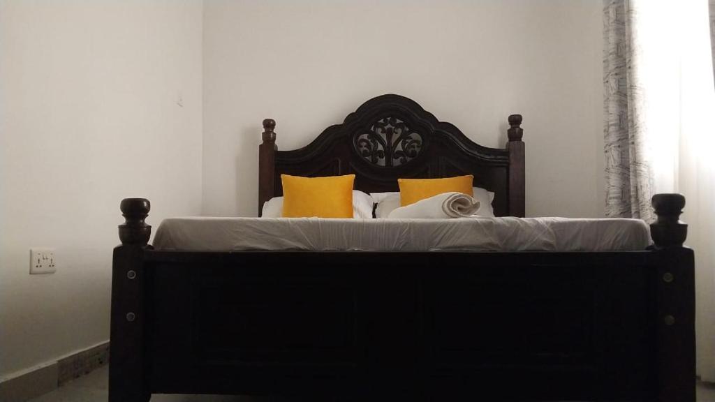 RuiruBonyeza Safaris Staycations-Kenya的一间卧室配有黑色床和黄色枕头