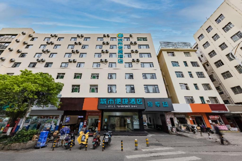 昆明City Comfort Inn Kunming Dashuying Yejin Hospital Wangdaqiao的一座大型白色建筑,前面停有摩托车