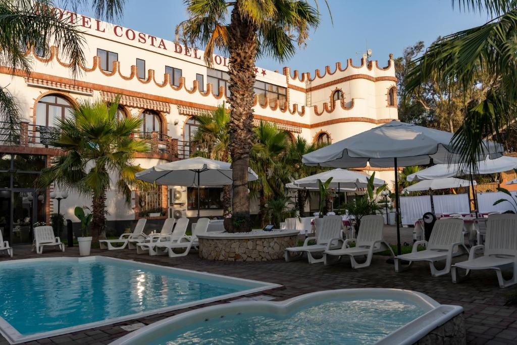 Vaccarizzo - DelfinoMg Palace Hotel Costa del Sole的一个带游泳池、椅子和遮阳伞的酒店