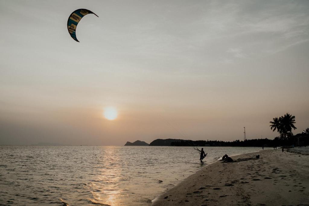 帕干岛Soukaina Beach Bungalow的一个人在海滩上玩风筝