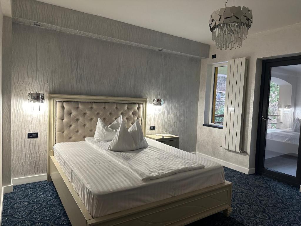 百乐·奥拉内斯蒂Pensiunea Izvoare Olanesti 3***的卧室配有一张带吊灯的大型白色床。
