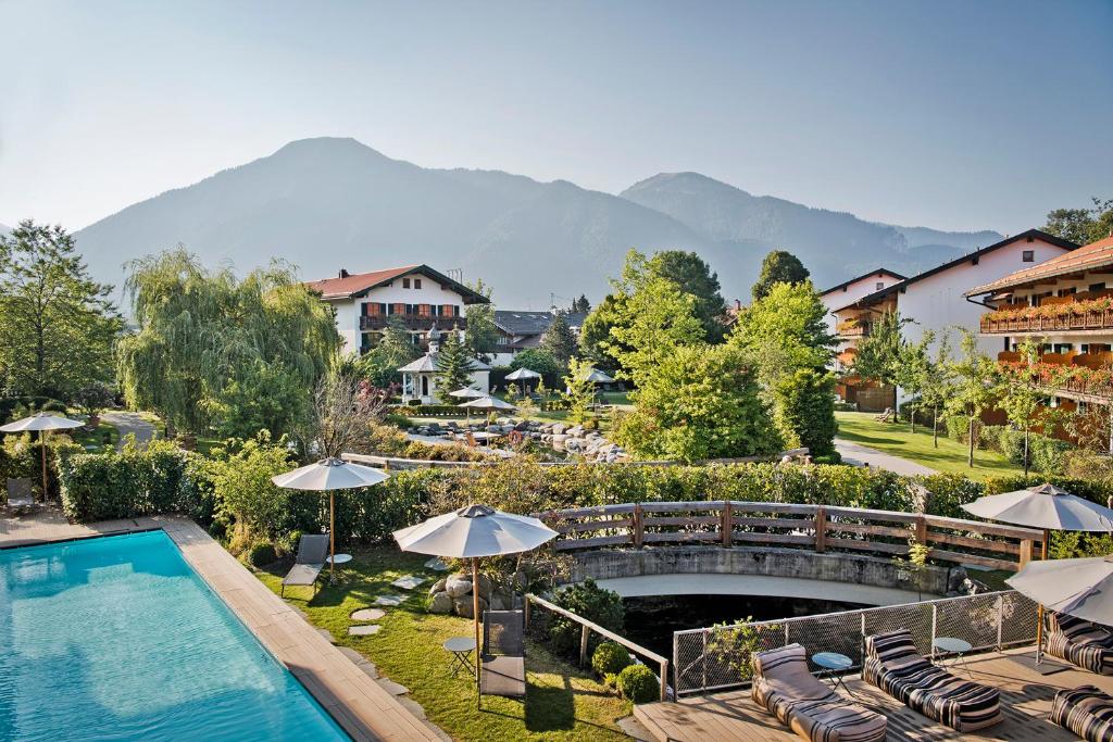 若特阿赫-埃根Spa & Resort Bachmair Weissach, LUXURY FAMILY RESORT的背景为一座带游泳池和山脉的酒店