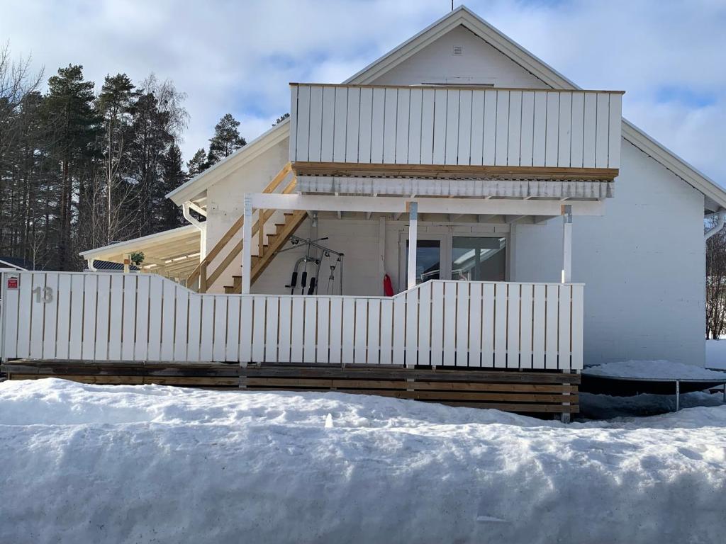 BurträskFin Villa nära insjön Burtäsket的雪中带白色围栏的房子