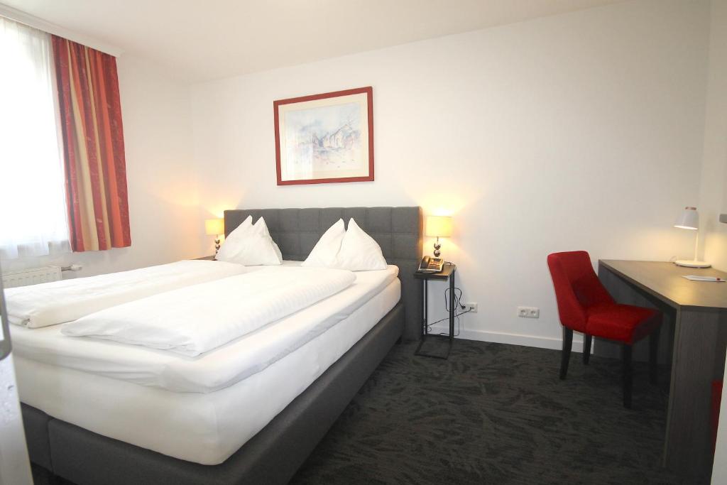 维也纳阿尔塔曼酒店的酒店客房设有一张大床和一张红色椅子。