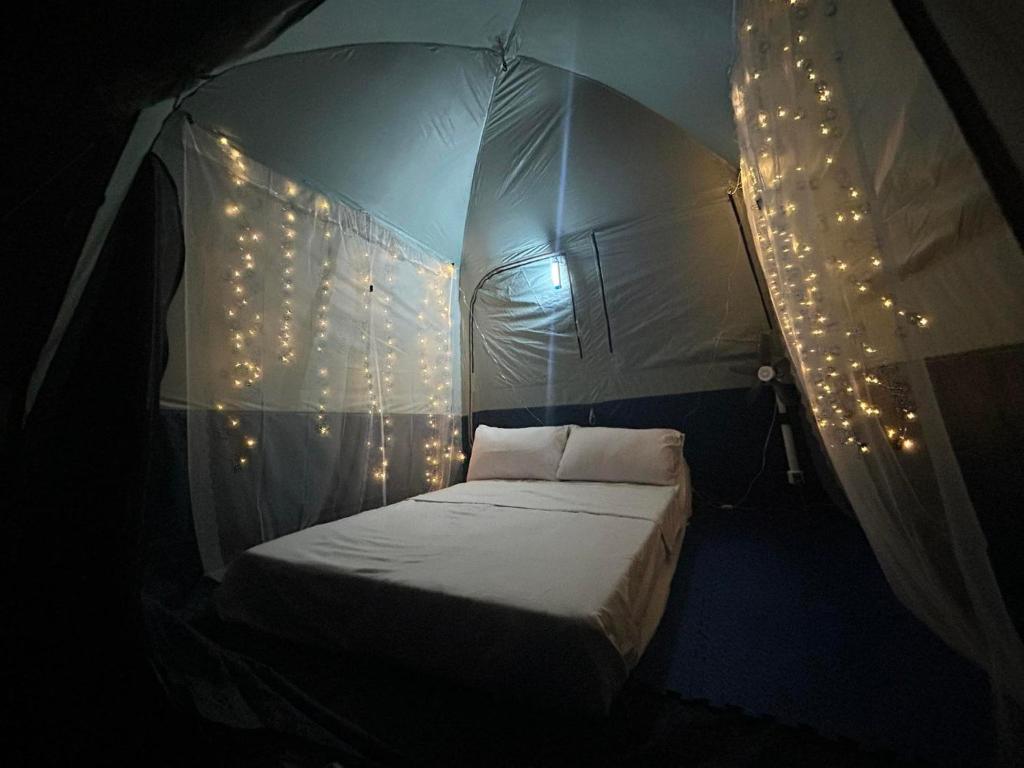 马尼拉Stargazing tent in Balcony at EKG House Rental的帐篷内的一张床位,配有圣诞灯