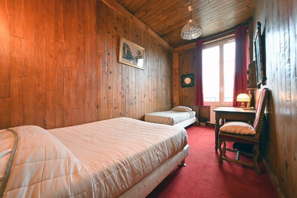 巴黎埃斯梅拉达酒店的一间卧室设有木墙、一张床和一张书桌