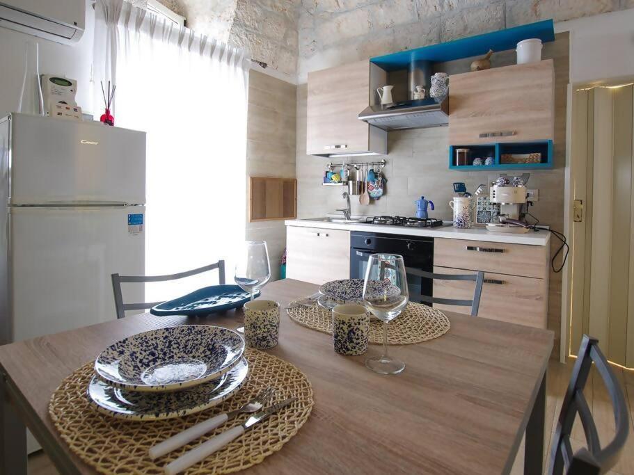奥斯图尼Antica Dimora Giusy的厨房配有带盘子和酒杯的桌子