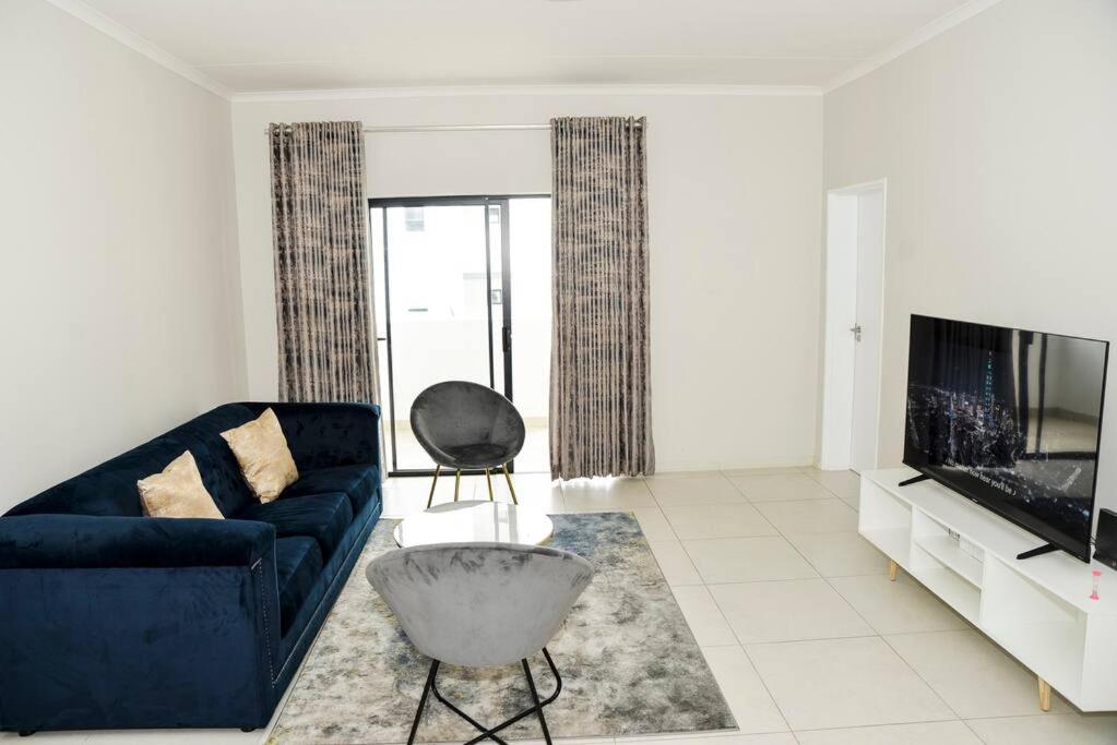 米德兰The Mansioners Apartment的客厅配有蓝色的沙发和电视
