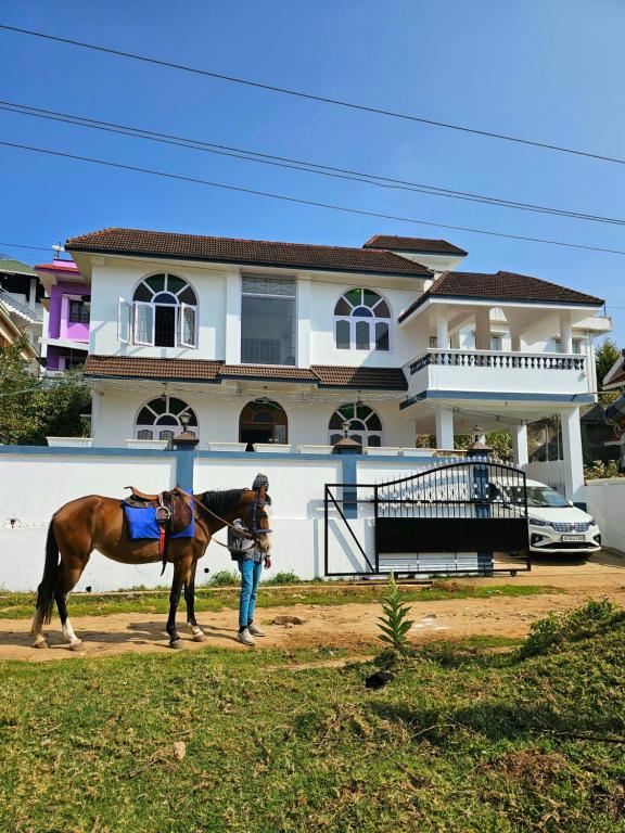 乌提Hestia Chalet 3BHK Villa的把马放在房子前面的人