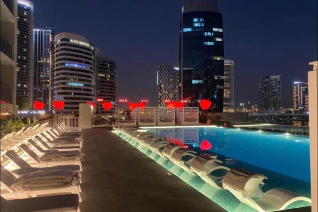 Al Faq‘Modern Apartment close to Burj Khalifa的一座带椅子的游泳池,晚上则享有城市天际线