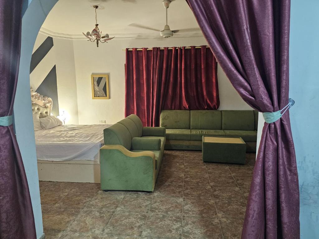 马斯喀特مدينة السلطان قابوس Sultan Qaboos city的一间卧室配有沙发和一张带红色窗帘的床