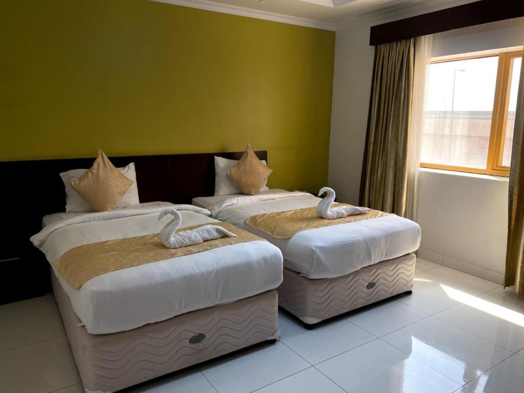 索哈尔SADARA HOTELS APARTMENTS的绿墙客房内的两张床