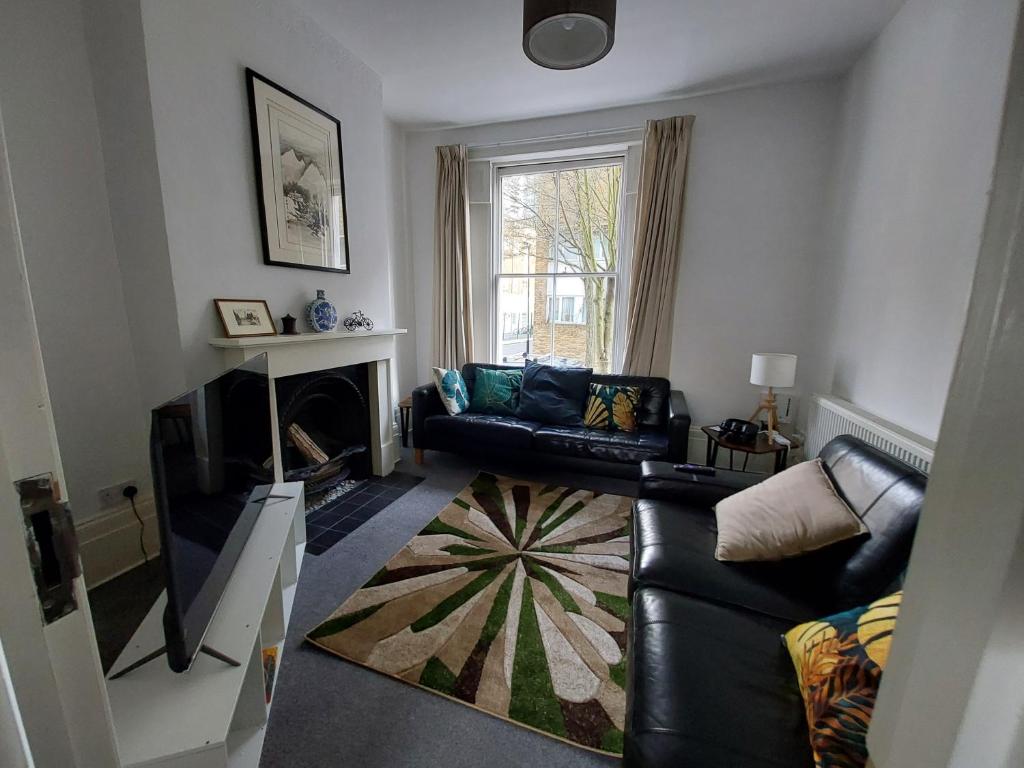 伦敦Large Serene Victorian Abode in Central London的客厅配有黑色真皮沙发和壁炉
