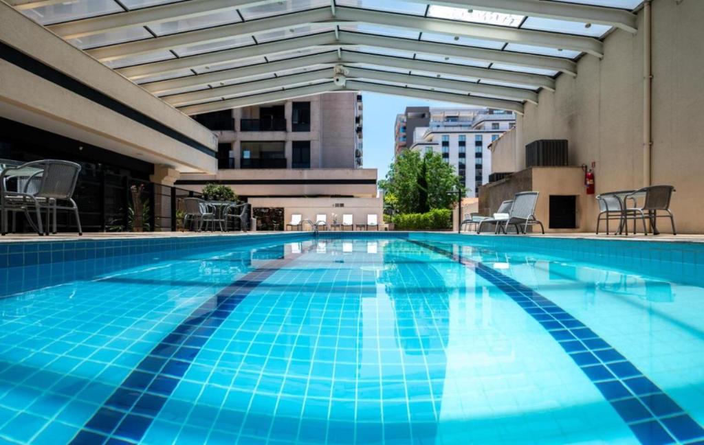 圣保罗Flat de Luxo Aeroporto Congonhas - Hotel eSuites的大楼内一个蓝色瓷砖的大型游泳池