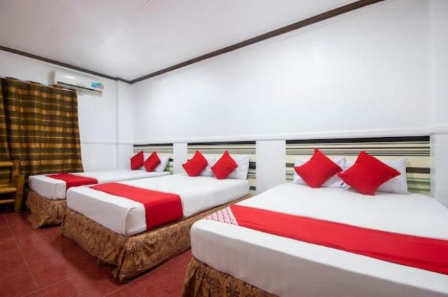 Lapu Lapu CityMax Travellers Inn的客房内的两张床和红色枕头