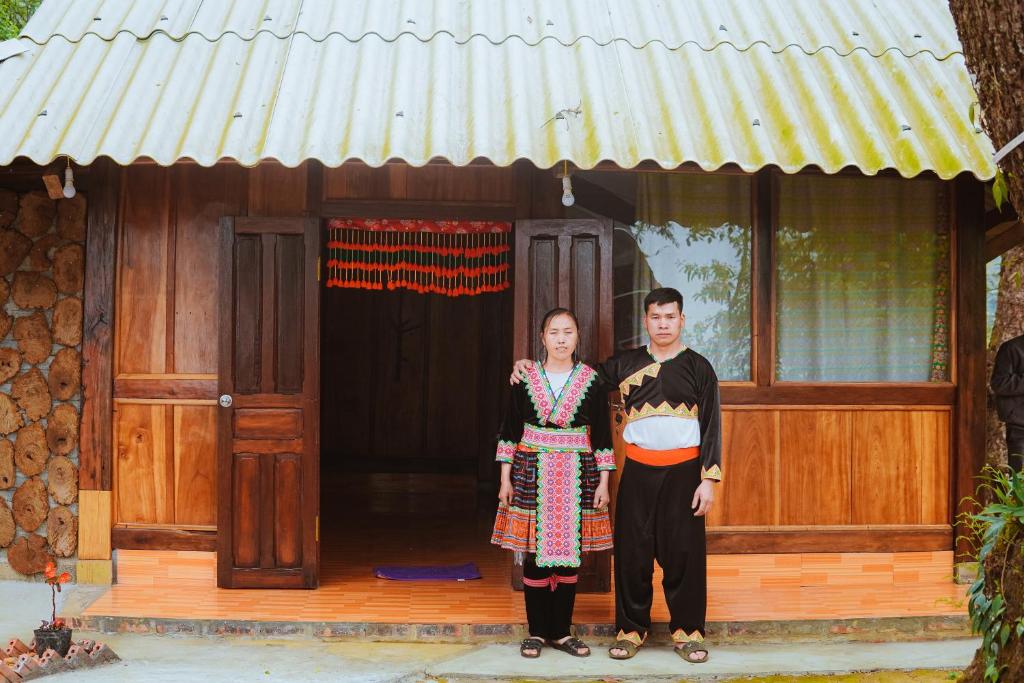 Phong ThổA Dế Homestay Sơn Tra的站在房子前面的男人和女人