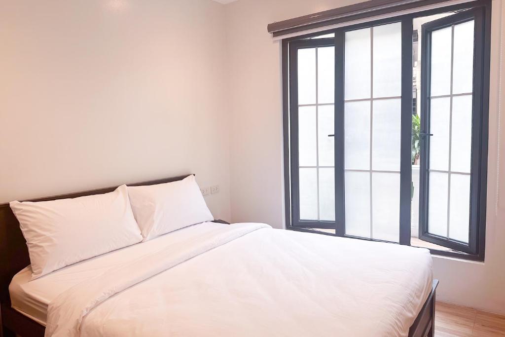 马尼拉SANTOS Pension House的带2扇窗户的客房内的一张白色床