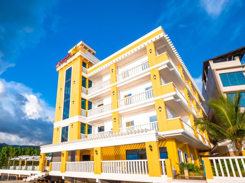 科隆巴拉望科隆阳光酒店的棕榈树的黄色和白色建筑