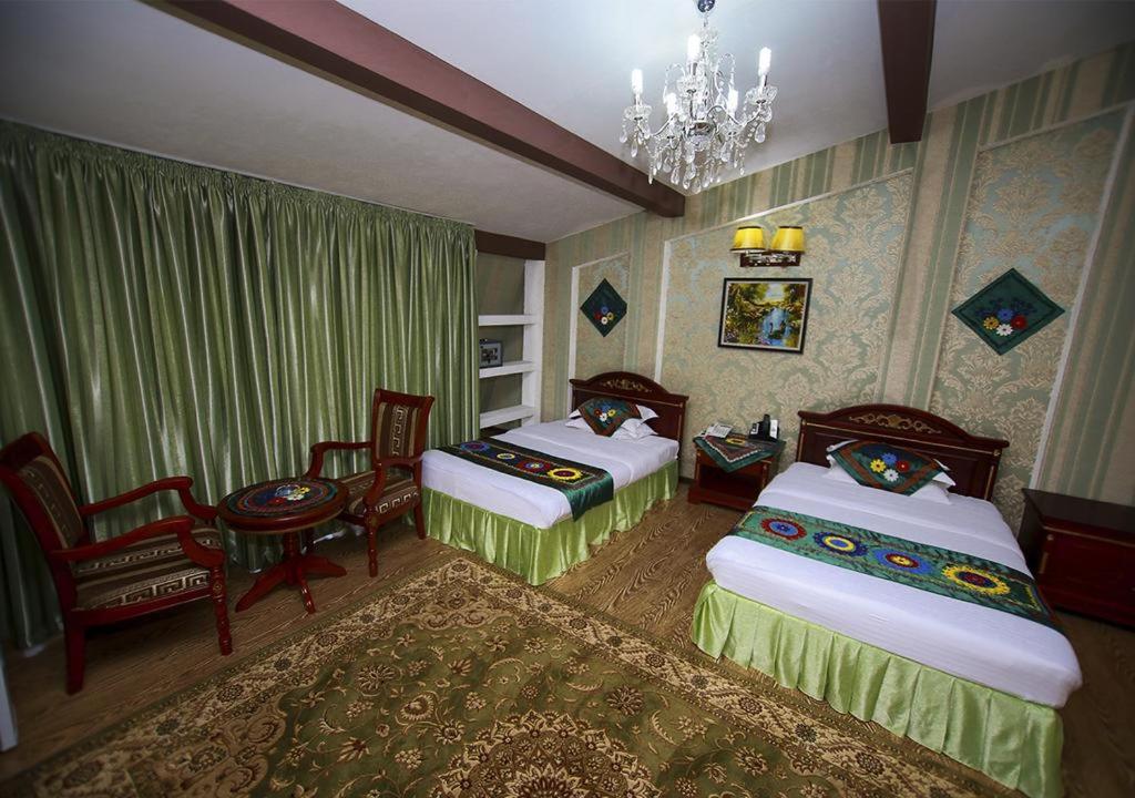 杜尚别ORIYO DUSHANBE HOTEL的一间卧室配有两张床、一把椅子和一个吊灯。