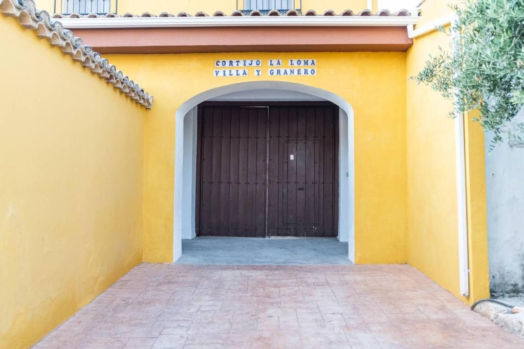 格拉纳达Casa Rural "compartida" La Loma Granero的黄色的建筑,带有棕色门的车库