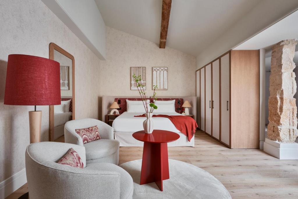 马略卡岛帕尔马波萨达特拉散塔精品酒店的一间卧室配有一张床和一张红色的桌子及椅子