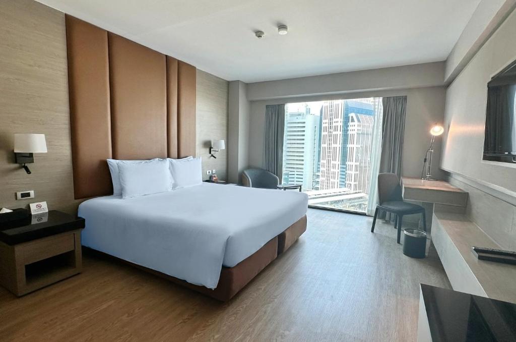 曼谷Ramada by Wyndham Bangkok Sukhumvit 11的一间酒店客房,设有一张大床和一个大窗户