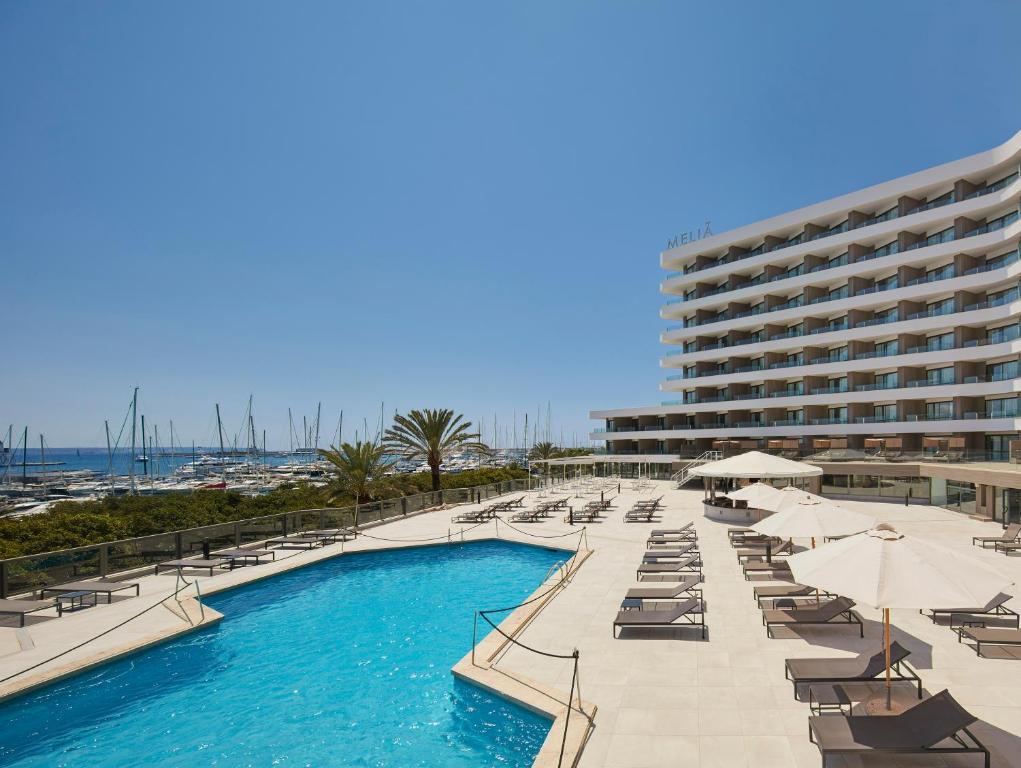 马略卡岛帕尔马梅利亚帕尔马码头酒店的一座带躺椅的游泳池以及一座大型建筑
