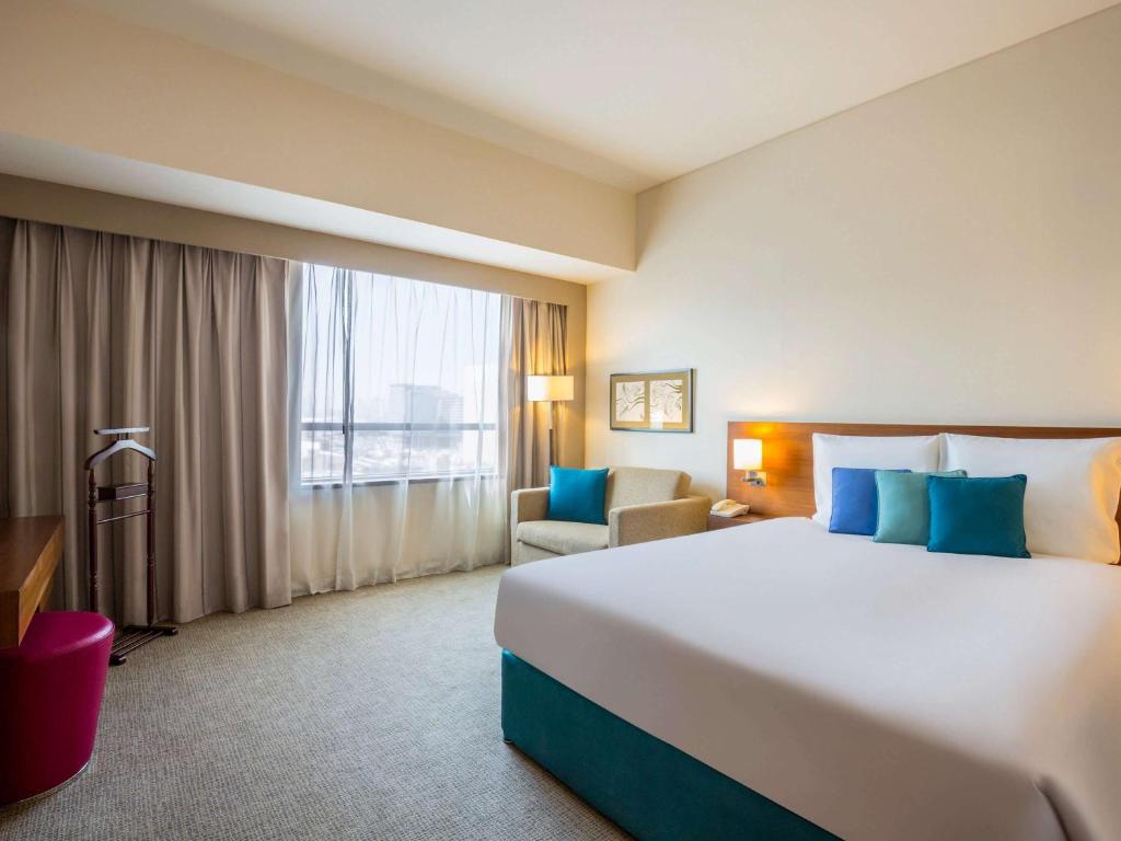 迪拜Novotel Deira Creekside Dubai的一间设有大床和窗户的酒店客房