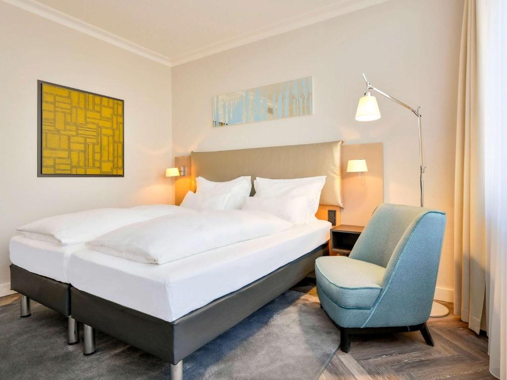科隆美居科隆贝佛斯特拉瑟酒店的一间卧室配有一张床和一张蓝色椅子