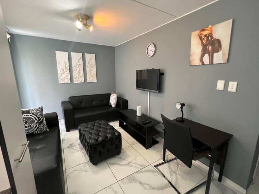 比勒陀利亚Beyond Comfort Apartment的客厅配有黑色沙发和电视