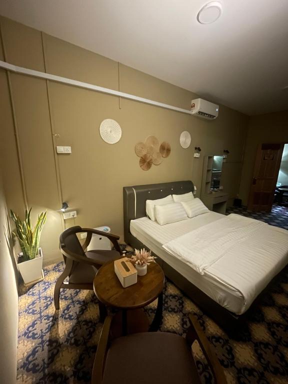 马六甲The Grand Bali Hotel的一间卧室配有一张床和一张桌子及椅子