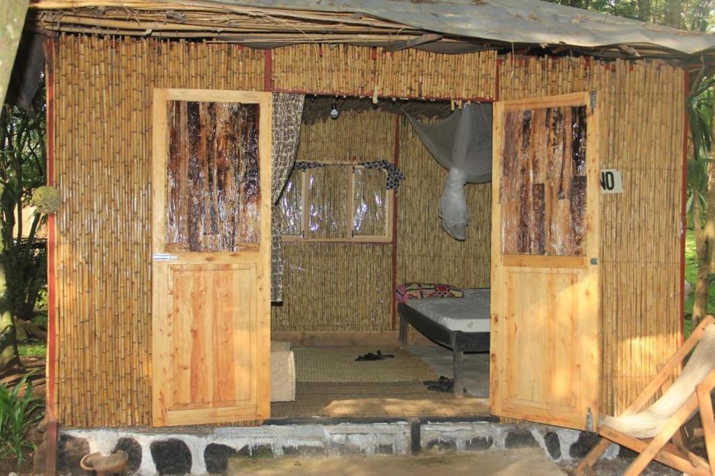 NyakinamaRed Rocks Rwanda - Bamboo Cottage的小小屋设有两扇门和一张床