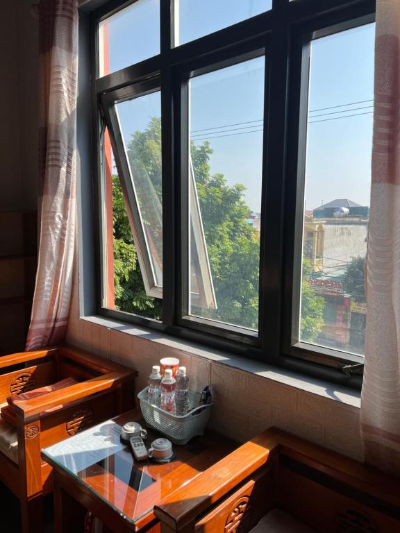 宁平Ninh Binh Central Backpackers hostel的一间房间,设有两个窗户,前面设有桌子