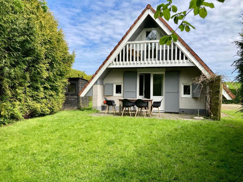 安于姆Olivia 6pers House with a private garden close to the National Park Lauwersmeer的院子里的白色房子,配有椅子和桌子