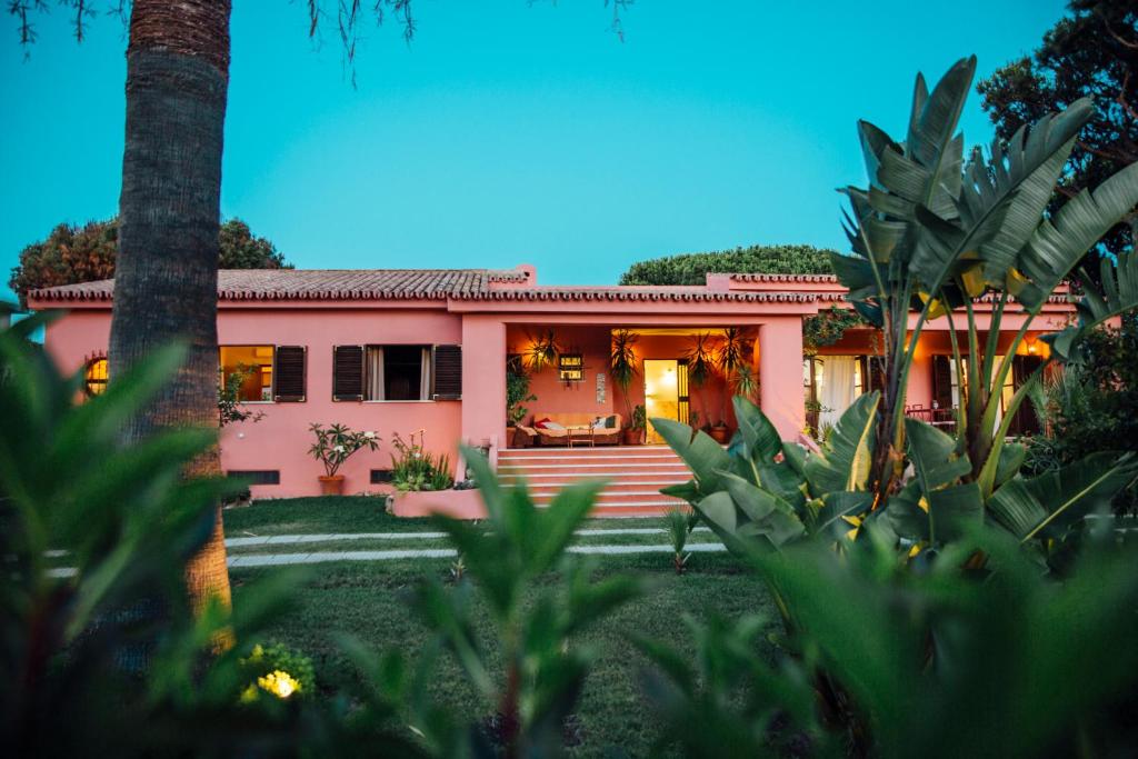 奎特里拉Charismatic Villa Pitanga Private pool and garden的一座粉红色的房子,前面有一棵棕榈树