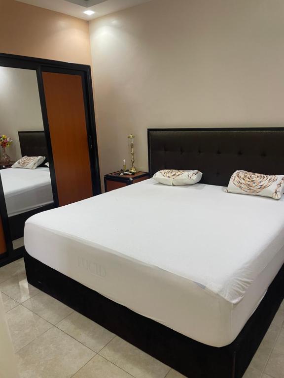 达喀尔Jumeau Lo的卧室配有一张带两个枕头的大白色床