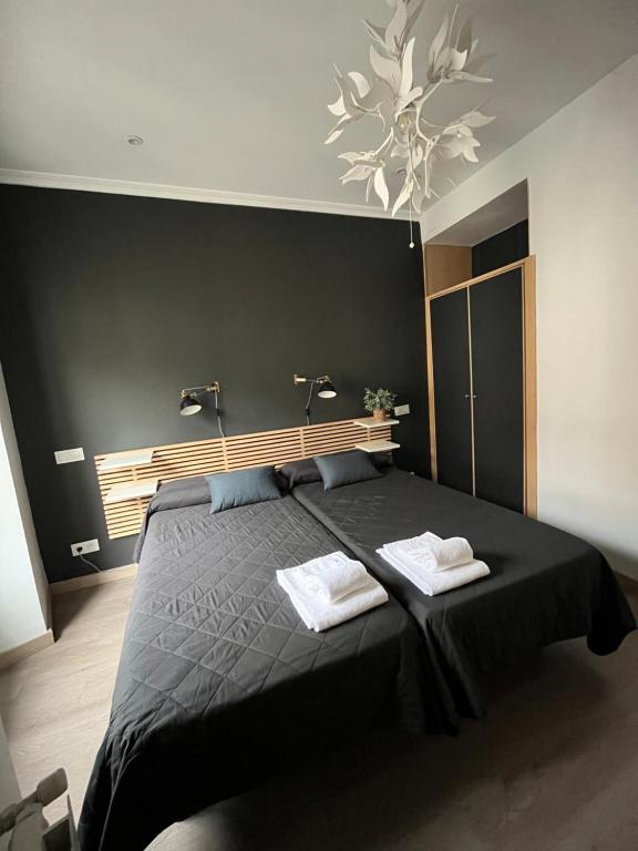 马德里马约尔广场英特尔旅馆的一间卧室配有一张黑色床和两条毛巾