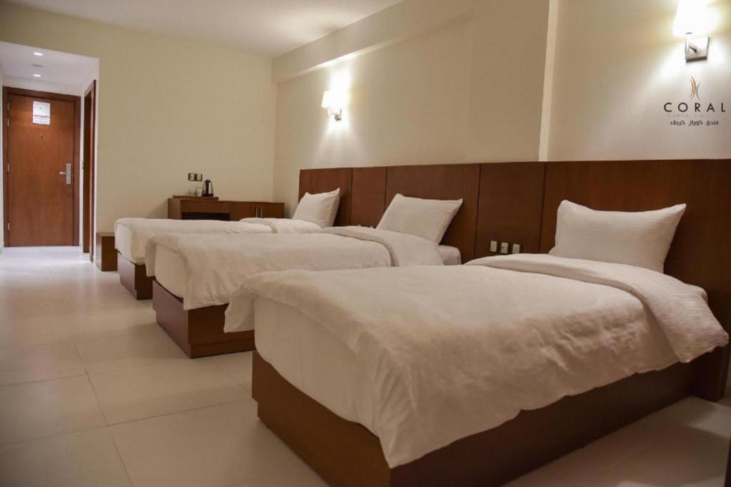 卡尔巴拉Coral Hotel Karbala的酒店客房,配有3张带白色床单的床