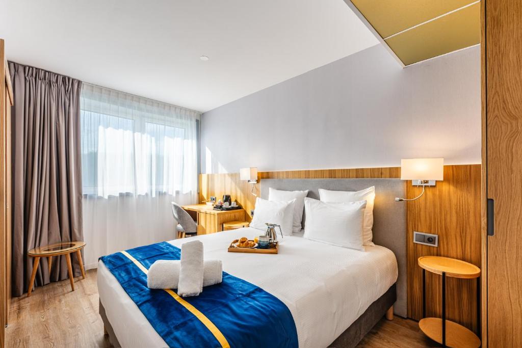 罗尼苏布瓦Brit Hotel Privilège Paris Rosny-sous-Bois的酒店客房设有一张大床和一张书桌。