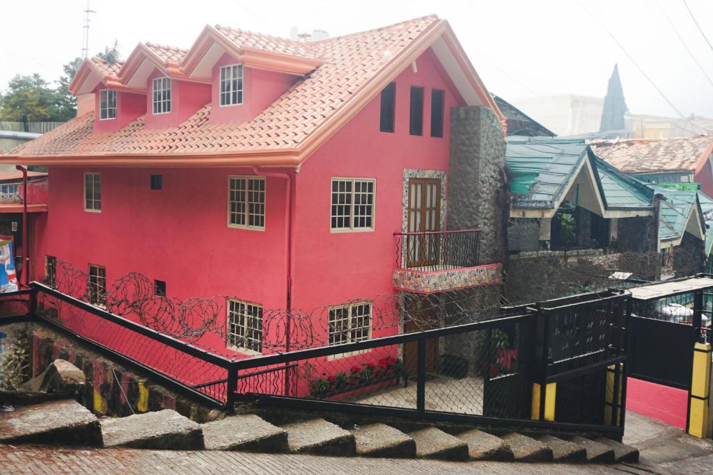 碧瑶Cozy Baguio House - Outlook Drive (DOT accredited)的前面有黑色栅栏的红色房子