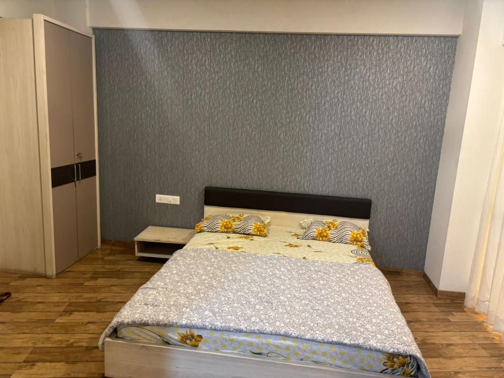 苏拉特Rajhans Belizia JSM的一间卧室配有一张带灰色墙壁的床