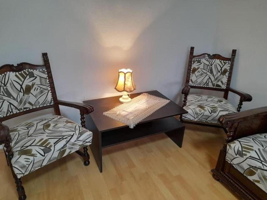 沙托劳尔尧乌伊海伊LBB apartman的一间设有两把椅子和一张带台灯的桌子的房间